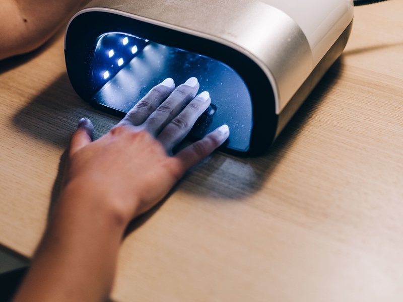A client's hand curing under a gel lamp.