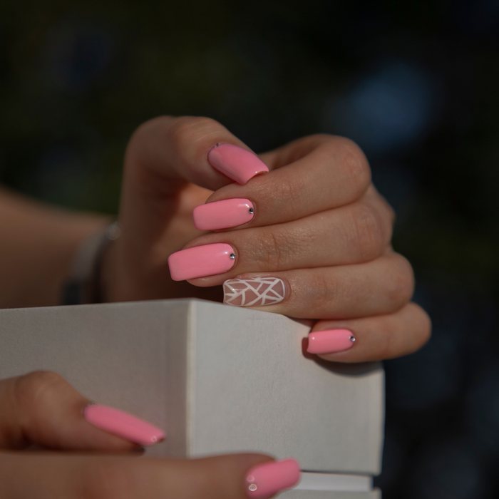 Pink square nails with tiny rhinestones and a white line-art accent nail.