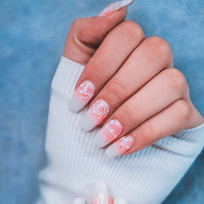 Long pink-and-white ombré nails with hand-painted white leaves.